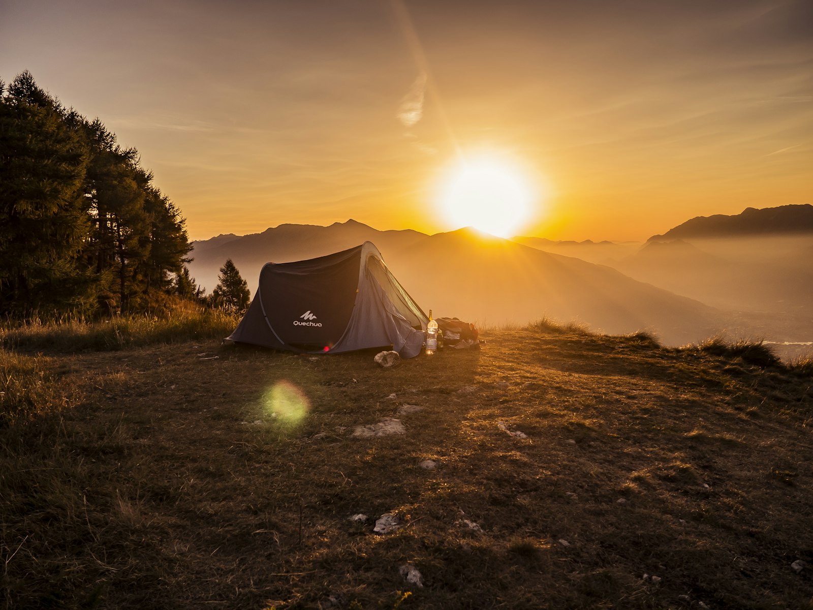Tent op een heuvel bij zonsondergang