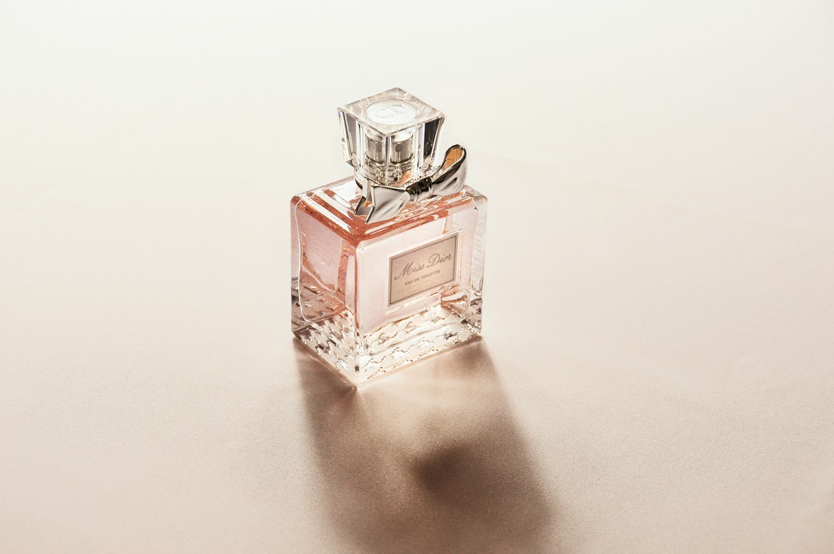Parfumfles met roze parfum op een lichte achtergrond