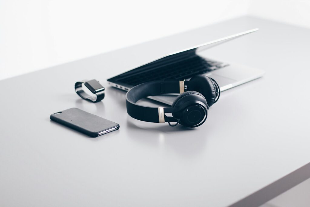 Laptop, smartphone, smartwatch en koptelefoon op een tafel