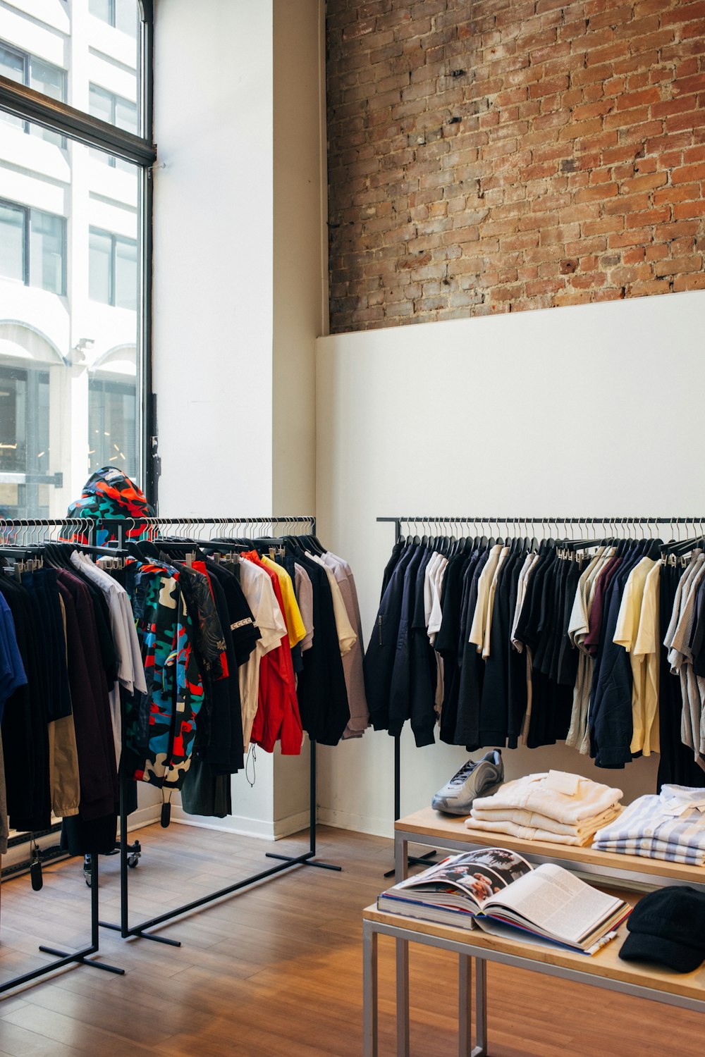 Kledingrekken met jassen en shirts in een winkel met bakstenen muur